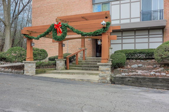 Front view of a building entrance with wooden pergola and festive decorations.