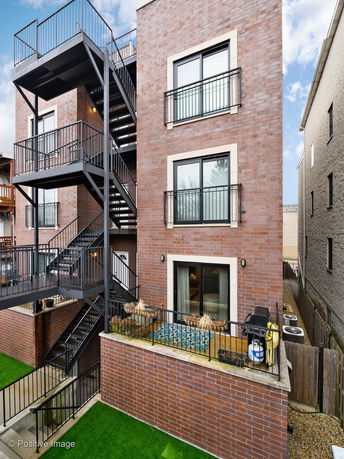 Rear view of a multi-story brick building with metal staircases and balconies.