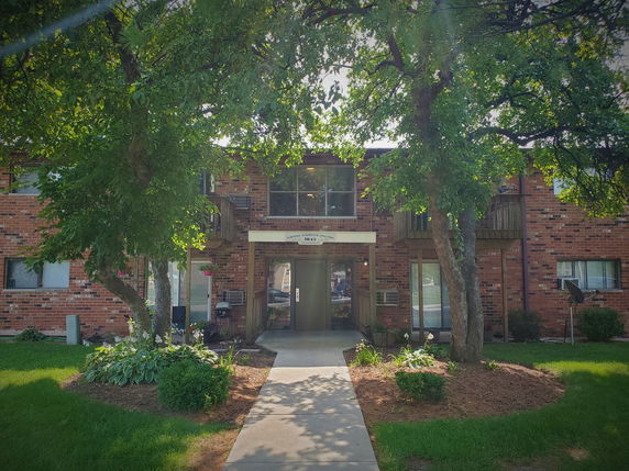 Front view of a two-story brick apartment building with balconies.