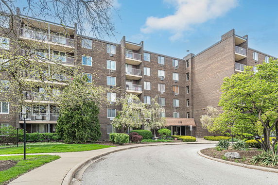 Front view of a multi-story brick apartment building with balconies.