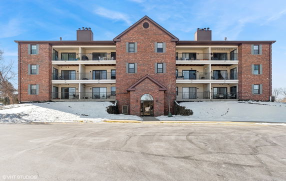 Front view of a multi-story brick apartment building with balconies.