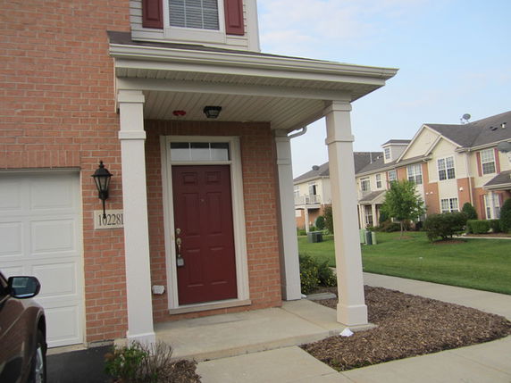 Front view of a house with a red door and a brick exterior.