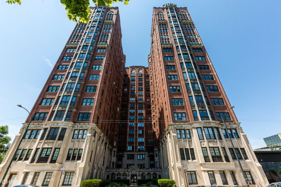 Front view of a tall, multi-story brick residential building with large windows.