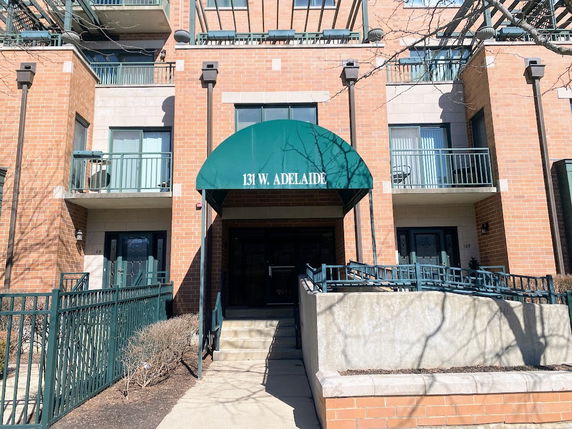 Front view of a brick apartment building with green awning entrance.