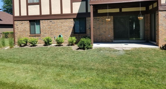 Front view of a brick house with sliding glass doors and hanging planters.