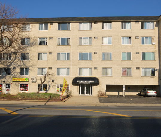 Front view of a multi-story apartment building with parking at ground level.