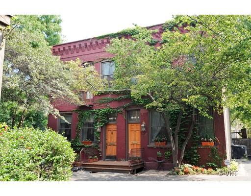Front view of a two-story brick house with two doorways and ivy climbing the facade.