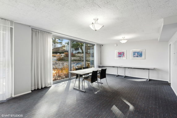 Indoor area with tables and chairs, large windows, and wall art.