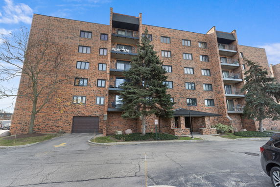 Front view of a multi-story brick apartment building with balconies.