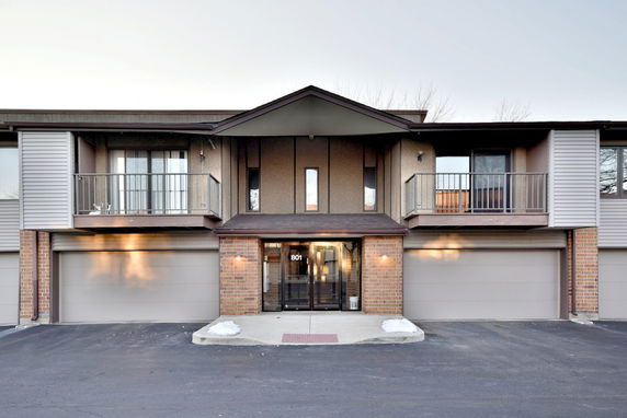 Front view of a two-story building with three garage doors and balconies.