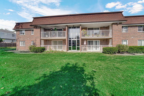 Front view of a brick apartment building with balconies.