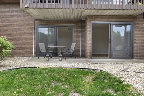 Front view of a building with sliding glass doors and a small patio area.