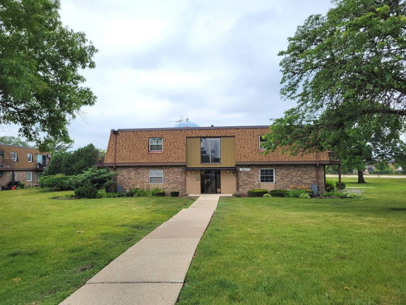 Front view of a two-story brick apartment building with a path leading to the entrance.