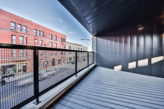 View from a building balcony overlooking a street with adjacent buildings.