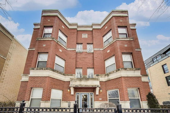 Front view of a multi-story brick building with large windows.
