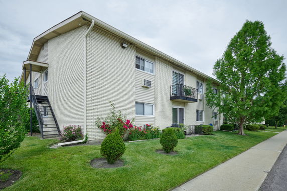 Front view of a two-story brick apartment building with balconies and external staircase.