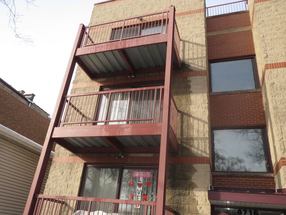 Front view of a multi-story building with balconies and large windows.