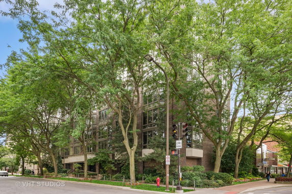 Front view of a multi-story building with large windows surrounded by trees.