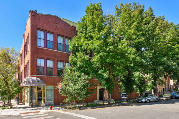 Front view of a multi-story brick building on a street corner.