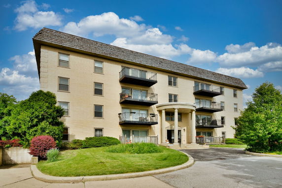 Front view of a four-story apartment building with balconies and a circular driveway.