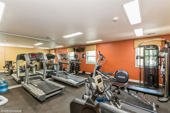 Indoor gym area with exercise equipment including treadmills and weights.