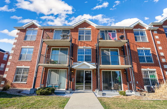 Front view of a three-story brick apartment building with balconies.