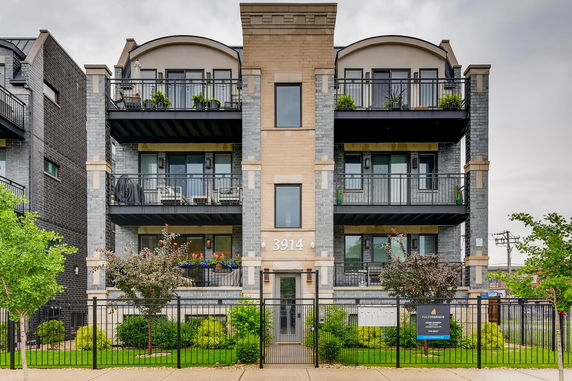 Front view of a multi-story residential building with balconies and a gated entrance.