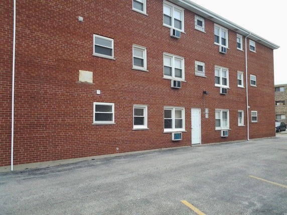 Front view of a brick apartment building with multiple windows and a white door.