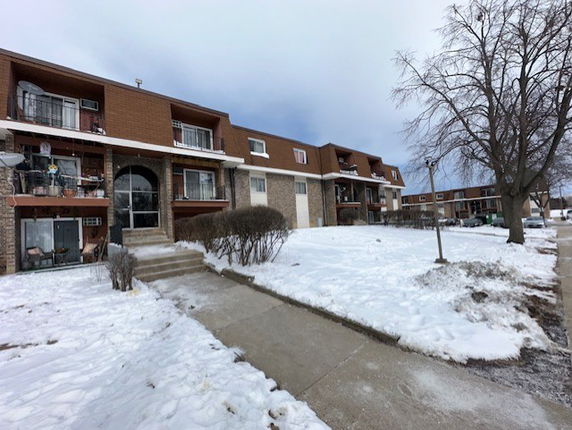 Front view of a row of two-story houses with balconies and snow-covered surroundings.