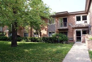 Front view of a two-story brick building with multiple windows and trees.