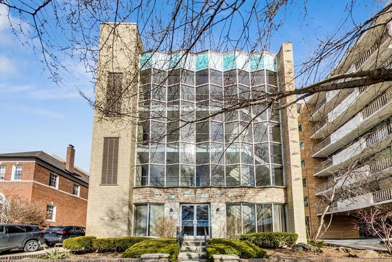 Front view of a multi-story building with large glass windows and two column structures on the sides.