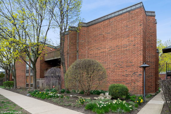 Front view of a brick building with a modern design and garden area.