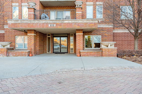 Entrance view of a brick building with balcony and glass doors.