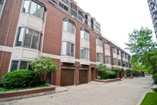 Front view of a multi-story brick building with large windows and garages.