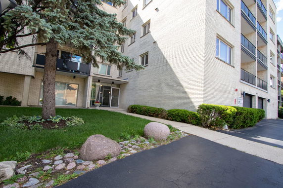 Front view of a multi-story apartment building with a brick exterior and balconies.