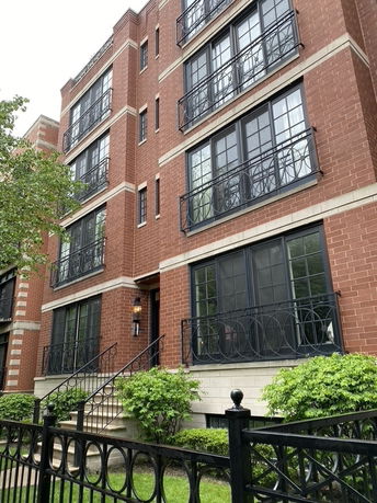 Front view of a multi-story brick building with decorative iron railings and large windows.