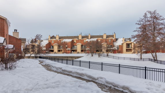Front view of a multi-story brick apartment building with balconies, in a snowy landscape.