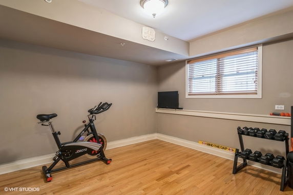 Room with stationary bike, weights, and a small TV for exercise.