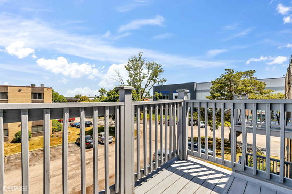 View from a balcony overlooking a parking area and nearby buildings.