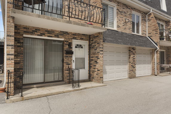 Front view of a townhouse with a brick exterior, balcony, and double garage.