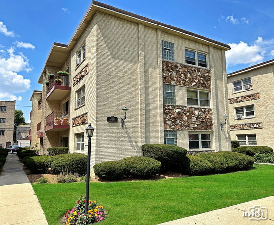 Front view of a multi-story apartment building with balconies and brick exterior.