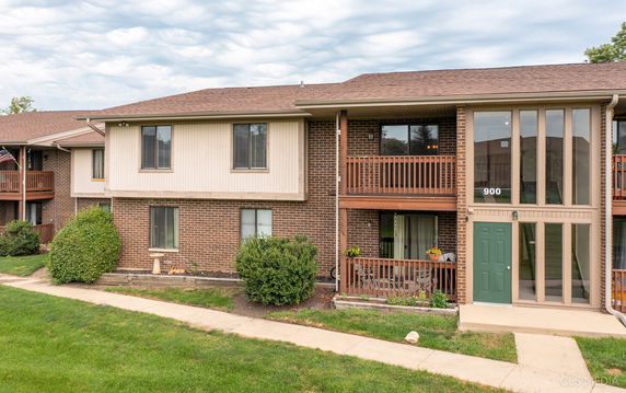 Front view of a two-story brick building with wooden balconies and green door entrance.