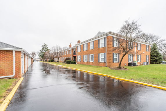 Front view of a two-story brick building with multiple windows and a side path.