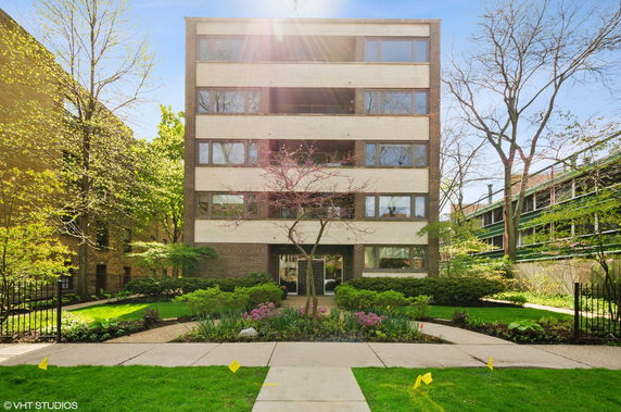 Front view of a multi-story building with large windows and a landscaped entrance.