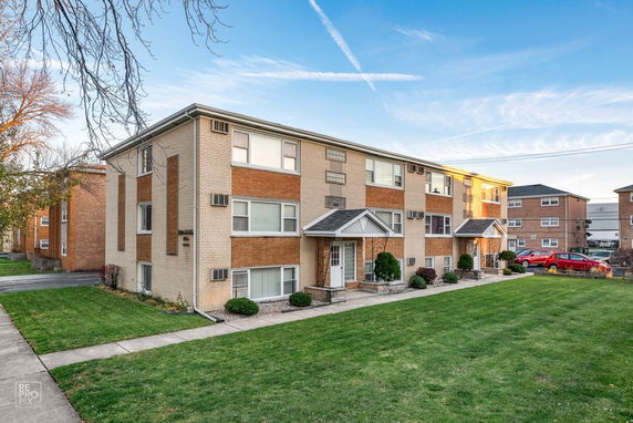 Front view of a two-story apartment building with brick facade and neatly trimmed landscaping.