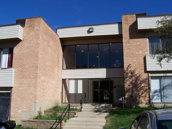 Front view of a brick apartment building with large glass windows.