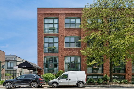 Front view of a brick multi-story building with large windows and a canopy entrance.