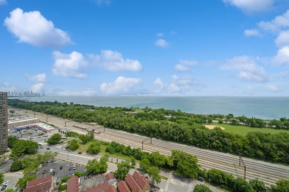 Panoramic view of a cityscape with water and rail tracks in the foreground.