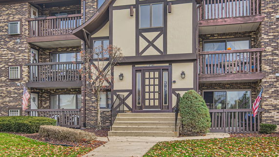 Front view of a multi-story residential building with balconies and a central entrance.