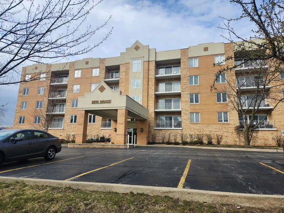 Front view of a multi-story apartment building with a covered entrance.